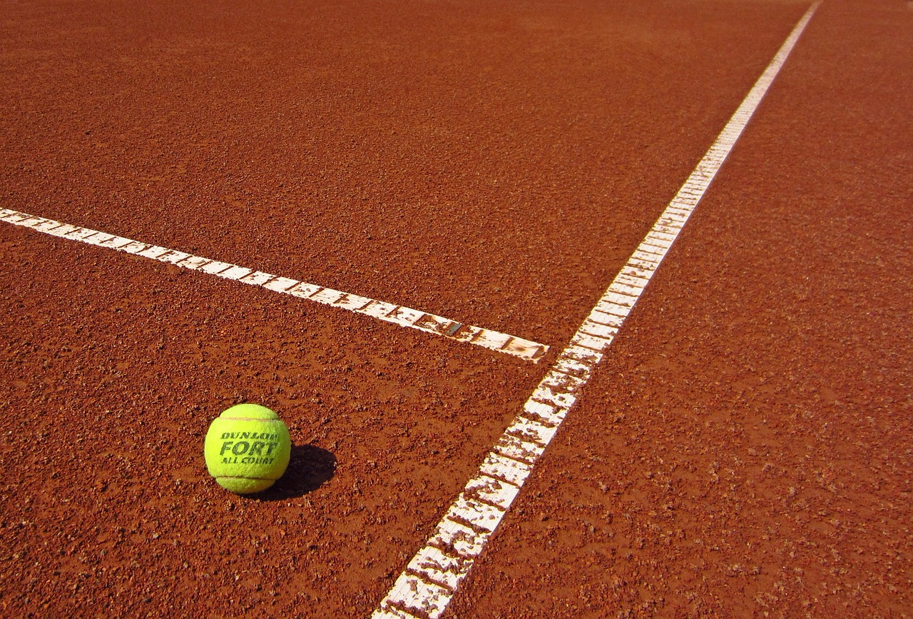 Tennisclub Ebstorf - 1 Tennisball auf einem roten Ascheplatz.