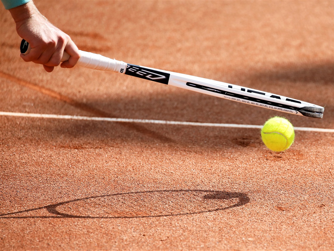 Tennisclub Ebstorf - Ein Tennisschläger bei der Ballaufnahme vom Boden.